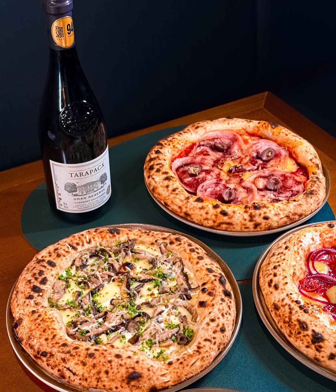 Pizzas napoletanas da Famiglia Mora à mesa com vinho